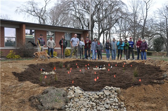 Photo of Bruce Drysdale Elementary rain garden design and construction team and partners standing in front of newly installed rain garden